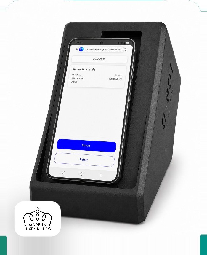Un smartphone inséré dans le socle du Q-Bot, affichant une demande de validation de transaction dans l'application LuxTrust