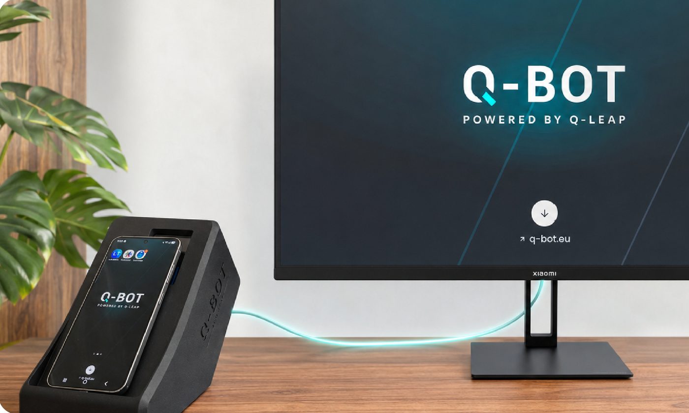 Le boîtier Q-Bot posé sur un bureau, un smartphone inséré dans son socle, l'interface web affichée sur l'écran voisin