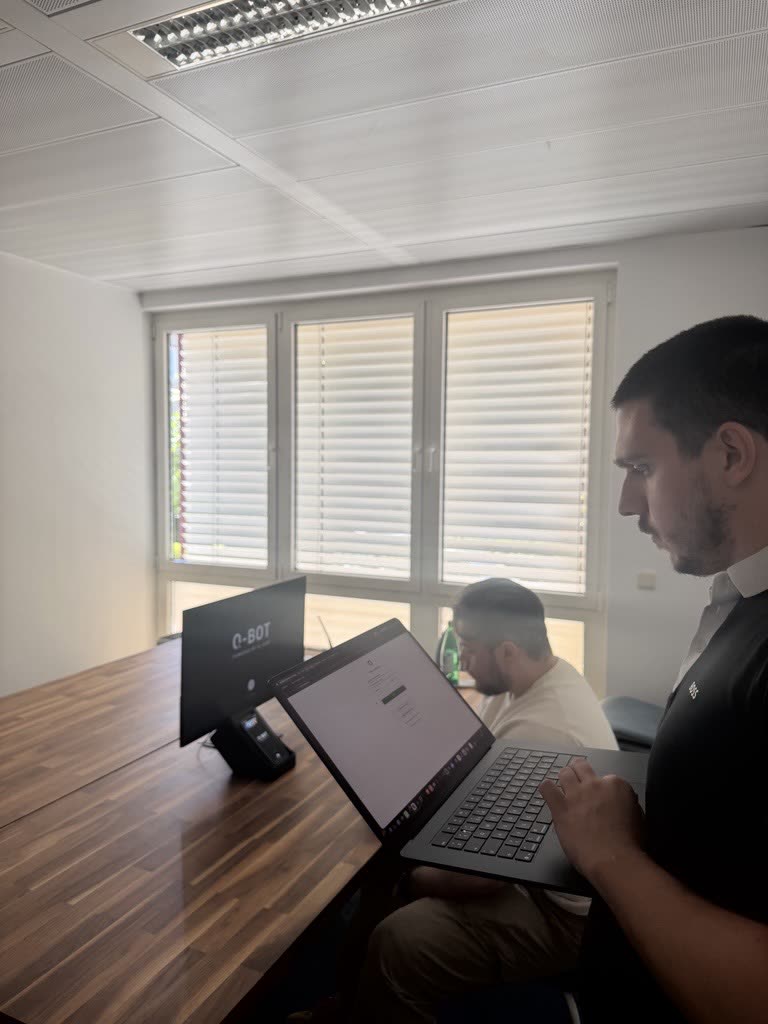 Deux membres de l'équipe Q-Leap au travail dans les bureaux de Bertrange, le boîtier Q-Bot posé sur la table