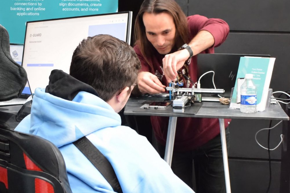 Deux membres de l'équipe Q-Leap devant un écran dans les bureaux de Q-Leap au Luxembourg, le boîtier Q-Bot posé sur la table et la signalétique Q-Bot au mur