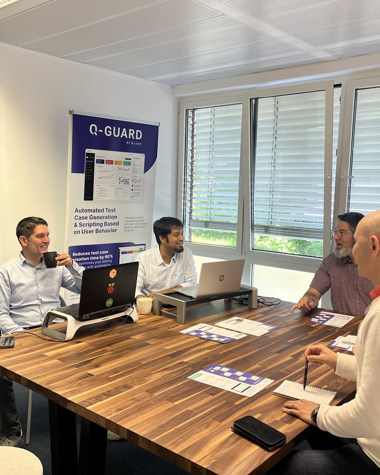 Réunion de l'équipe Q-Leap dans les bureaux du Luxembourg, devant les kakemonos Q-Leap et Q-Guard